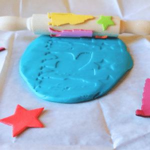 Cylinder seal craft with a decorated wooden roller making impressions in blue modelling dough